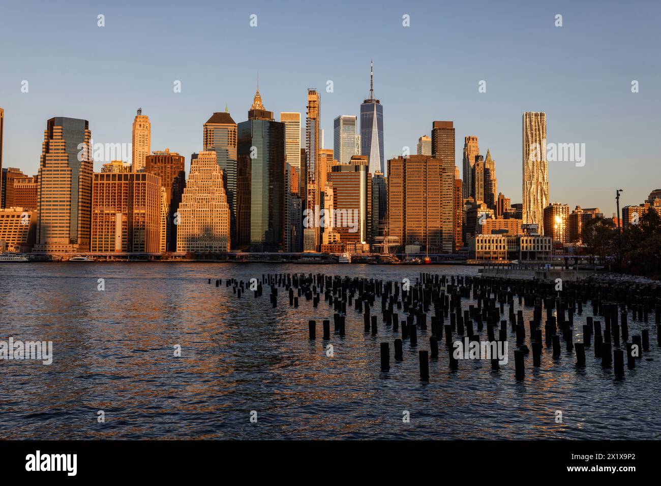 Wolkenkratzer im Finanzviertel Lower Manhattan, die am frühen Morgen New York über den East River vom Old Pier 1 im Brooklyn Bridge Park Greenway aus gesehen werden Stockfoto