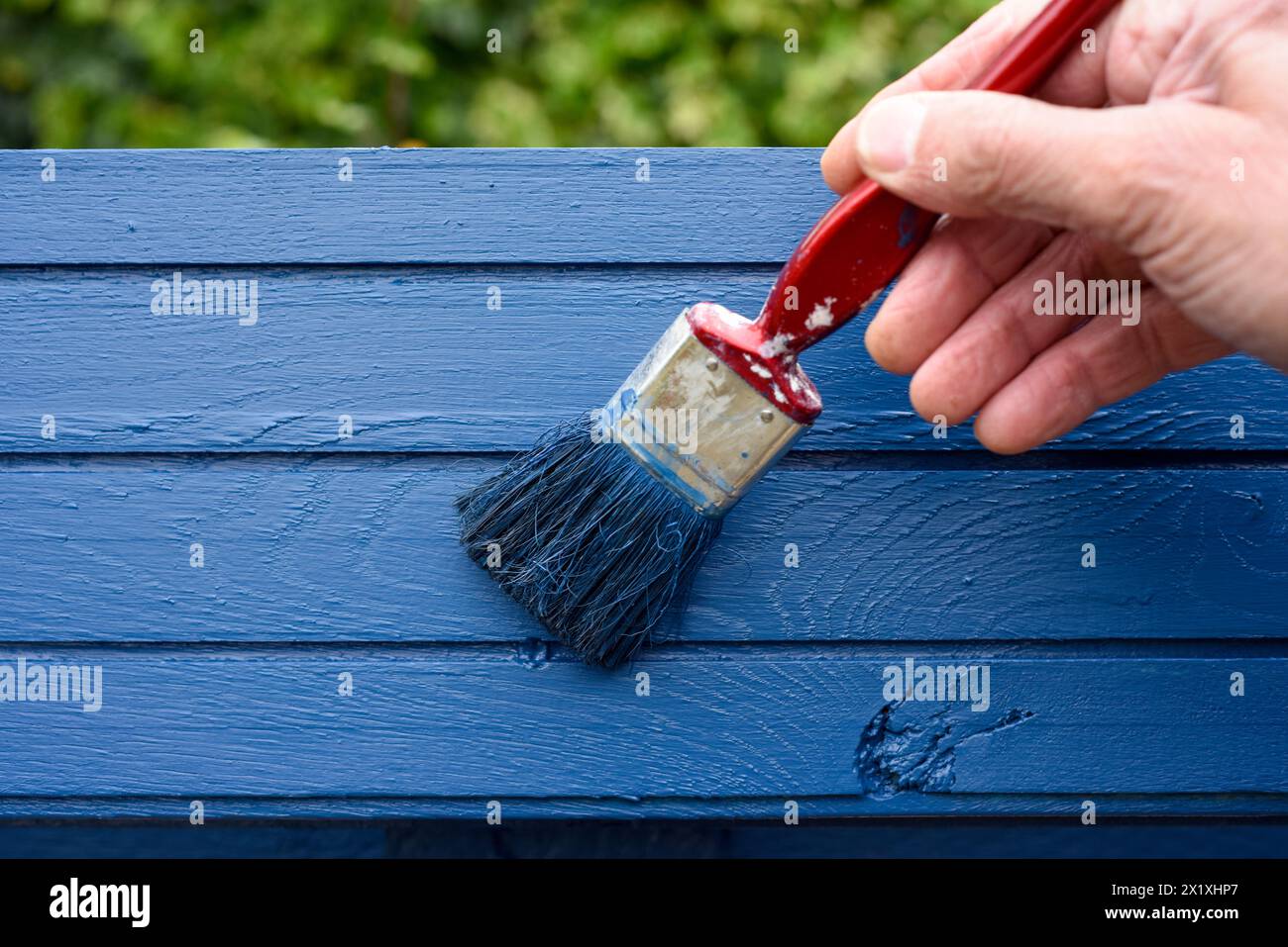 Männliche Hand mit einem Pinsel auf eine Holzplatte malen Stockfoto