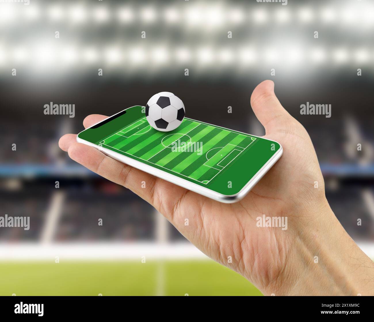Freigestellte Aufnahme eines Mannes, der ein Smartphone als Fußballfeld benutzt, online zuschauen, online wetten Konzept im Stadion Stockfoto