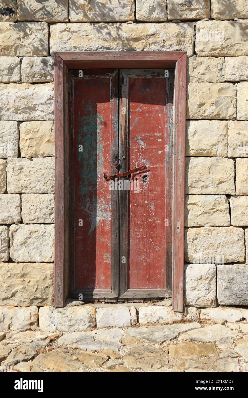 Eine geschlossene Holztür mit abblätternder roter Farbe. Stockfoto