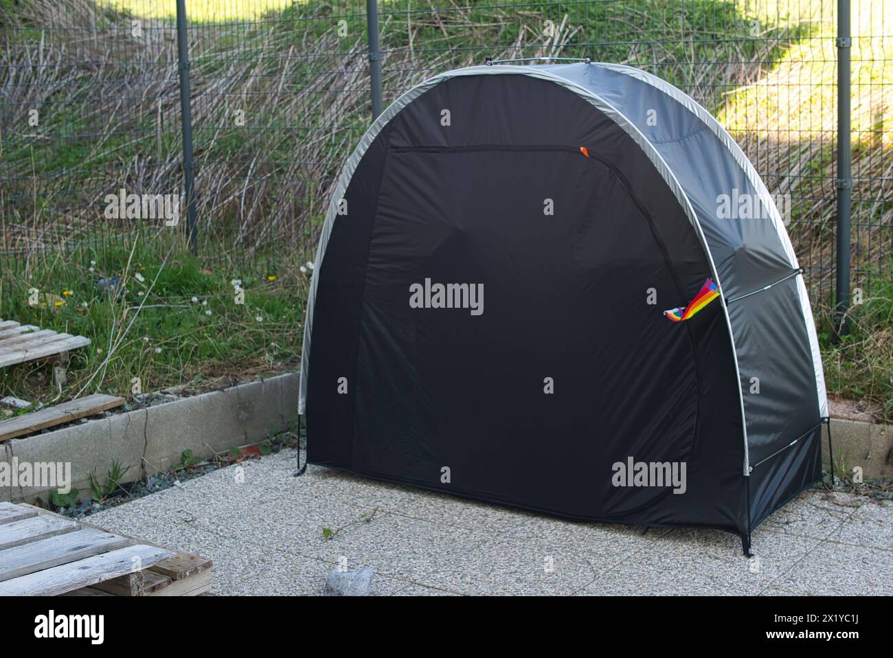 Geschlossenes schwarzes Zelt mit einer Regenbogenfahne im Verschluss. Kontext: Camping, LGBTQ+, schwul, lesbisch, homosexuell, bisexuell, Sexualität, Einzäunung, s Stockfoto