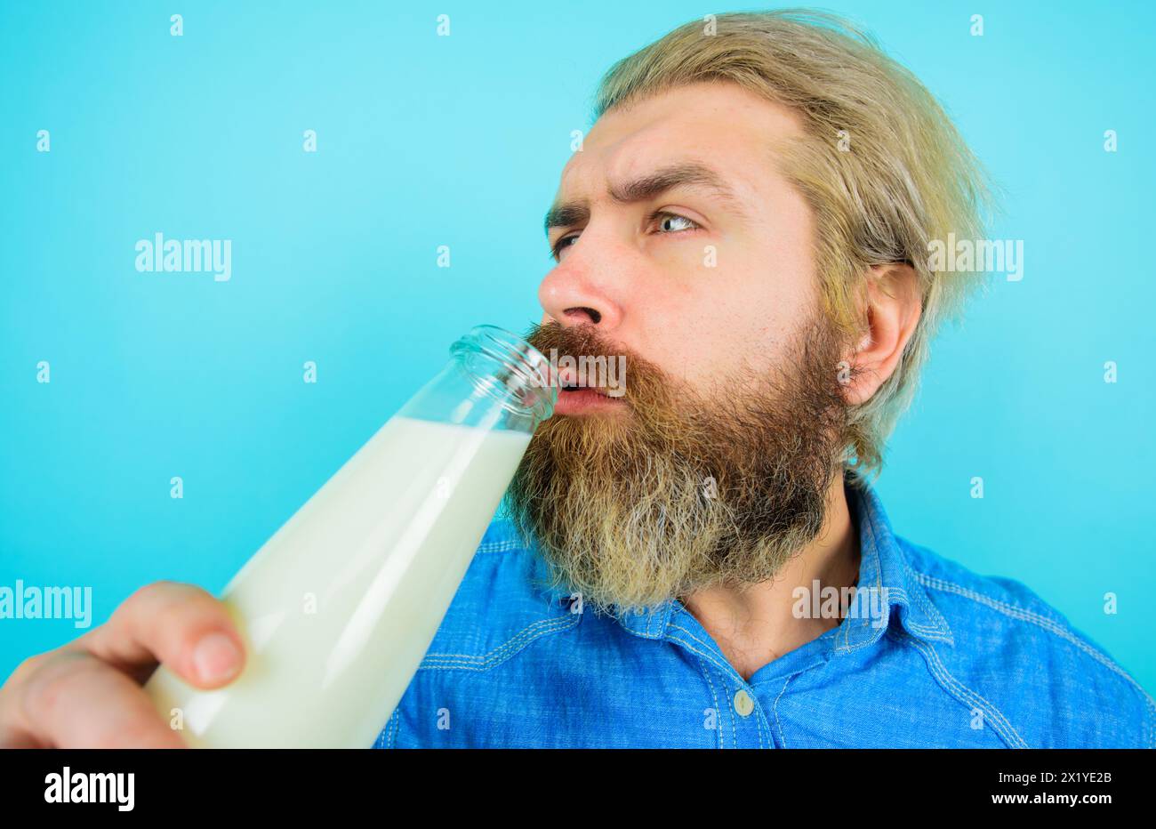 Ein bärtiger Mann trinkt frische Milch. Hübscher Mann in Denim-Hemd mit einer Flasche Milch oder Milchshake. Genießen Sie Bio-Produkte. Laktosefreie Milch oder vegane Milch Stockfoto