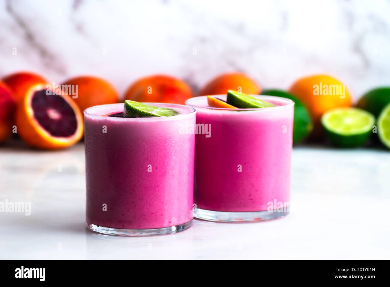 Zwei Margaritas aus Kokosnussblut und Limettengarne: Ein paar pastellrosa Tequila-Cocktails, die über Eiswürfeln in Steingläsern serviert werden Stockfoto