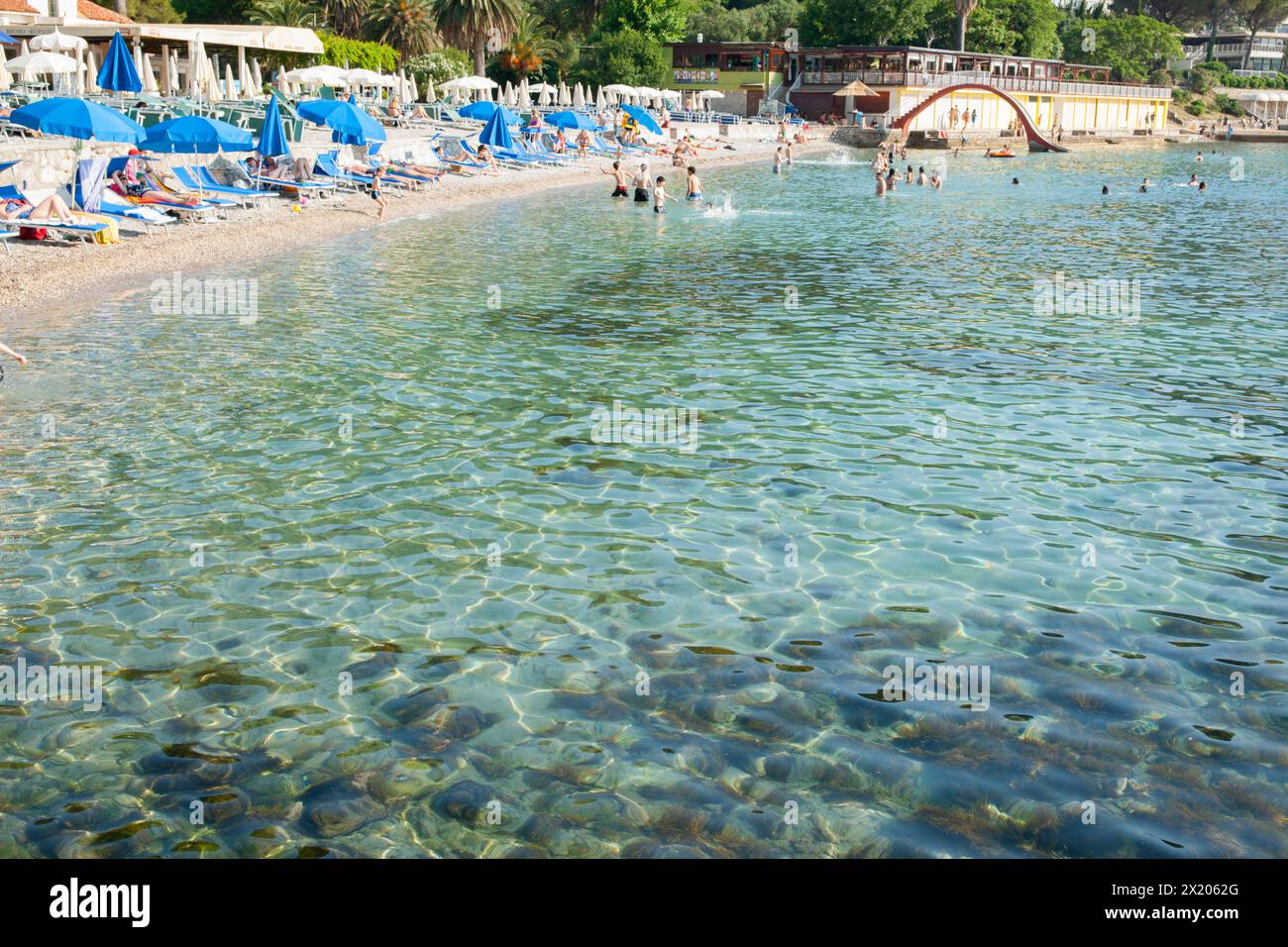 Dubrovnik Kroatien - 29. Mai 2011; redaktioneller überfüllter Uvala Lapad Strand mit Menschen und blauem Schirm. Stockfoto