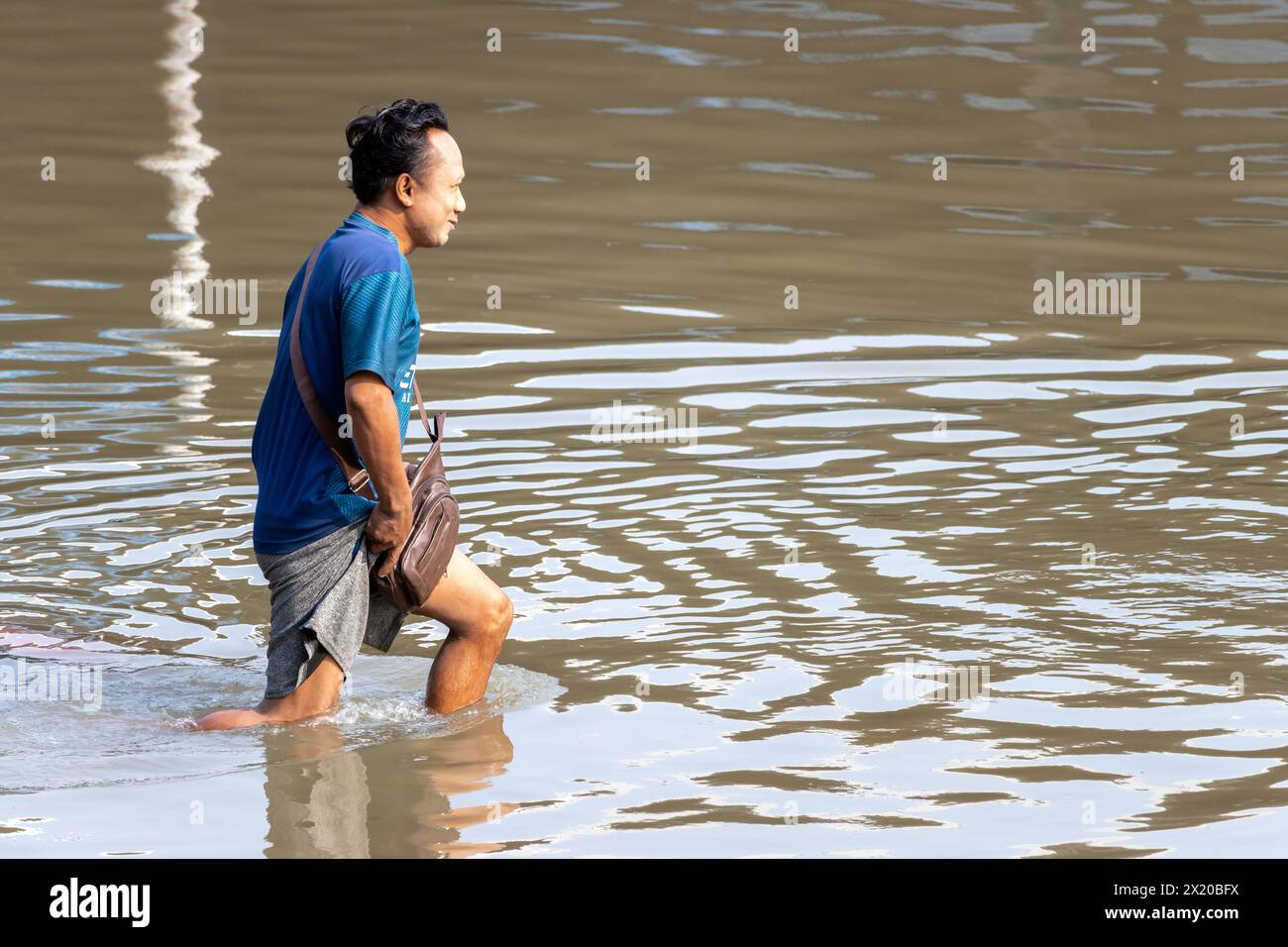 SAMUT PRAKAN, THAILAND, 11. Februar 2024, Ein fröhlicher Mann geht durch eine überflutete Straße Stockfoto