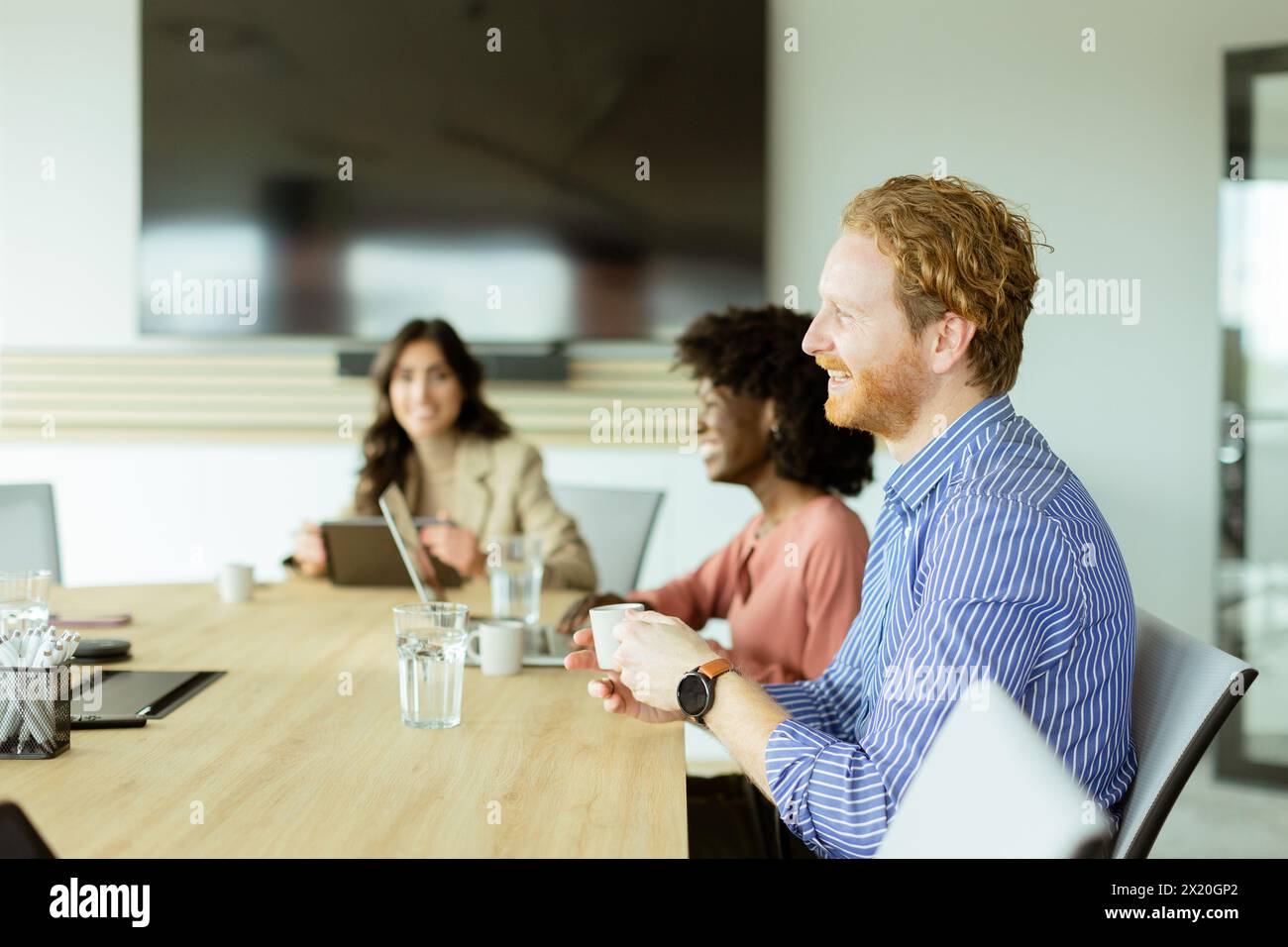 Eine multikulturelle Gruppe von Fachleuten arbeitet an einem Konferenztisch mit digitalen Geräten zusammen Stockfoto