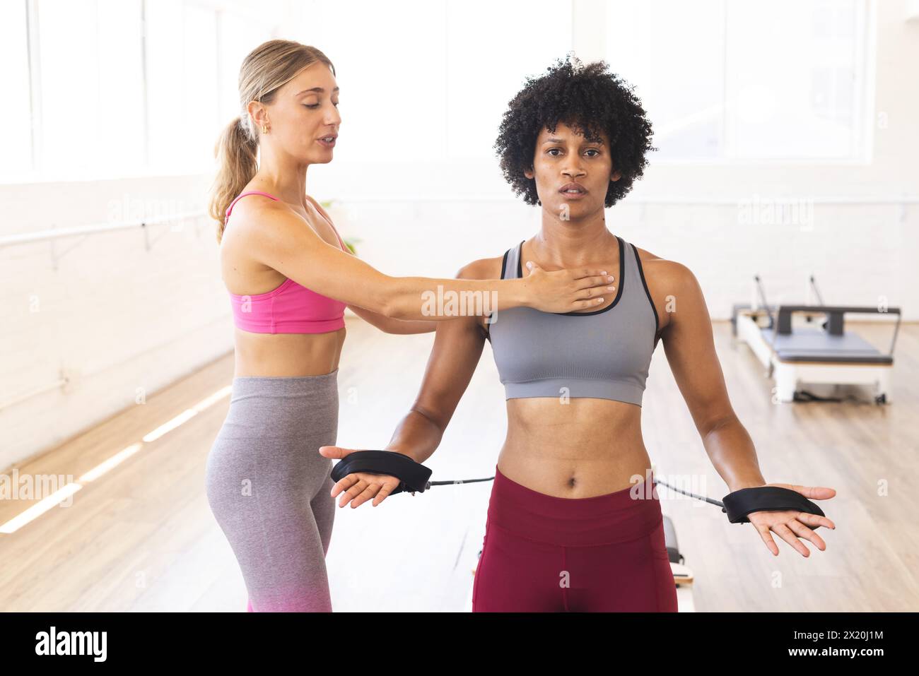 Kaukasische Frau, die die Haltung der birassischen Frau im Pilates-Studio einstellt Stockfoto