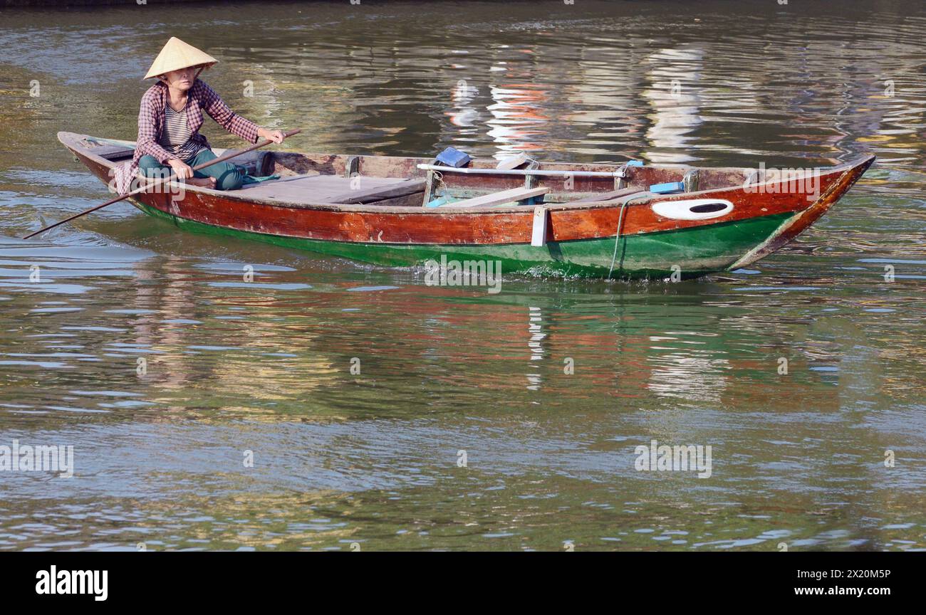 Eine vietnamesische Frau, die Güter oder Menschen über den Fluss Thu Bon in Hội an, Vietnam, transportiert. Stockfoto