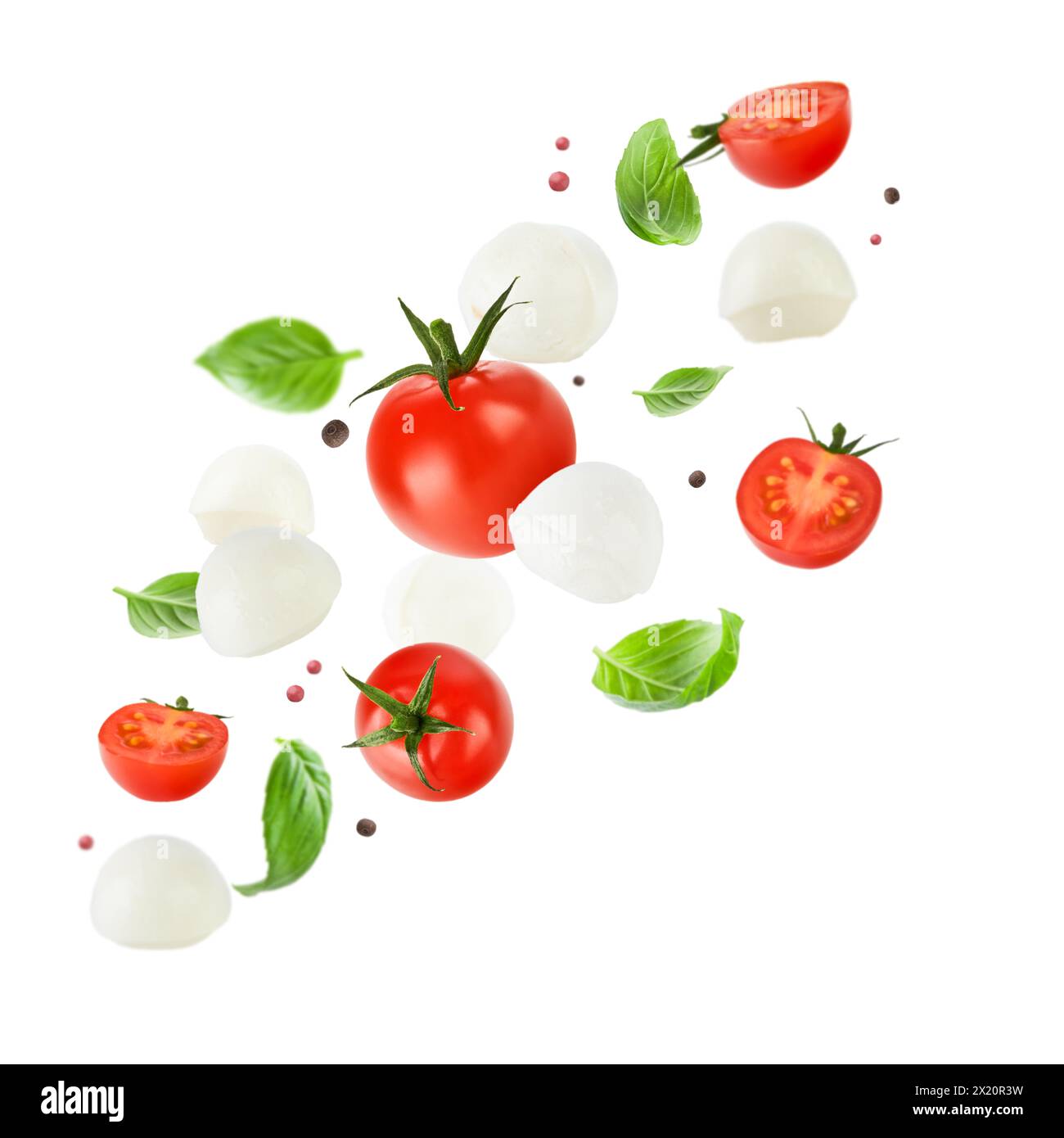 Fliegende Mozzarella-Käsebällchen, Tomaten, Basilikumblätter und Pfeffer für Caprese-Salat isoliert auf weißem Hintergrund. Mockup für Werbung oder Produ Stockfoto