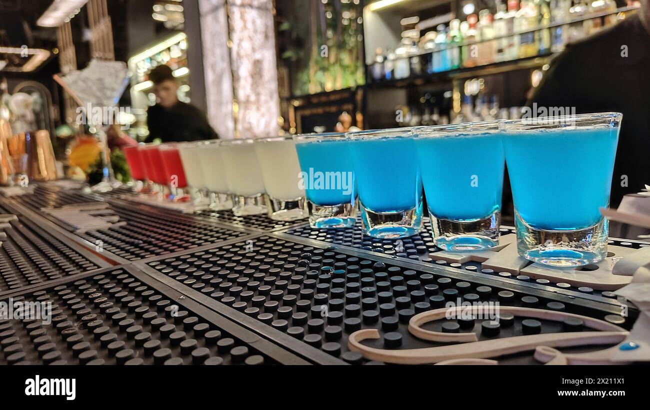 Blue Lagoon, White Cosmopolitan und Pink Lady Cocktail Shots werden in Serie für eine Gruppe von Freunden platziert, die sie im heißen Sommer an der Bar genießen können. Club A Stockfoto