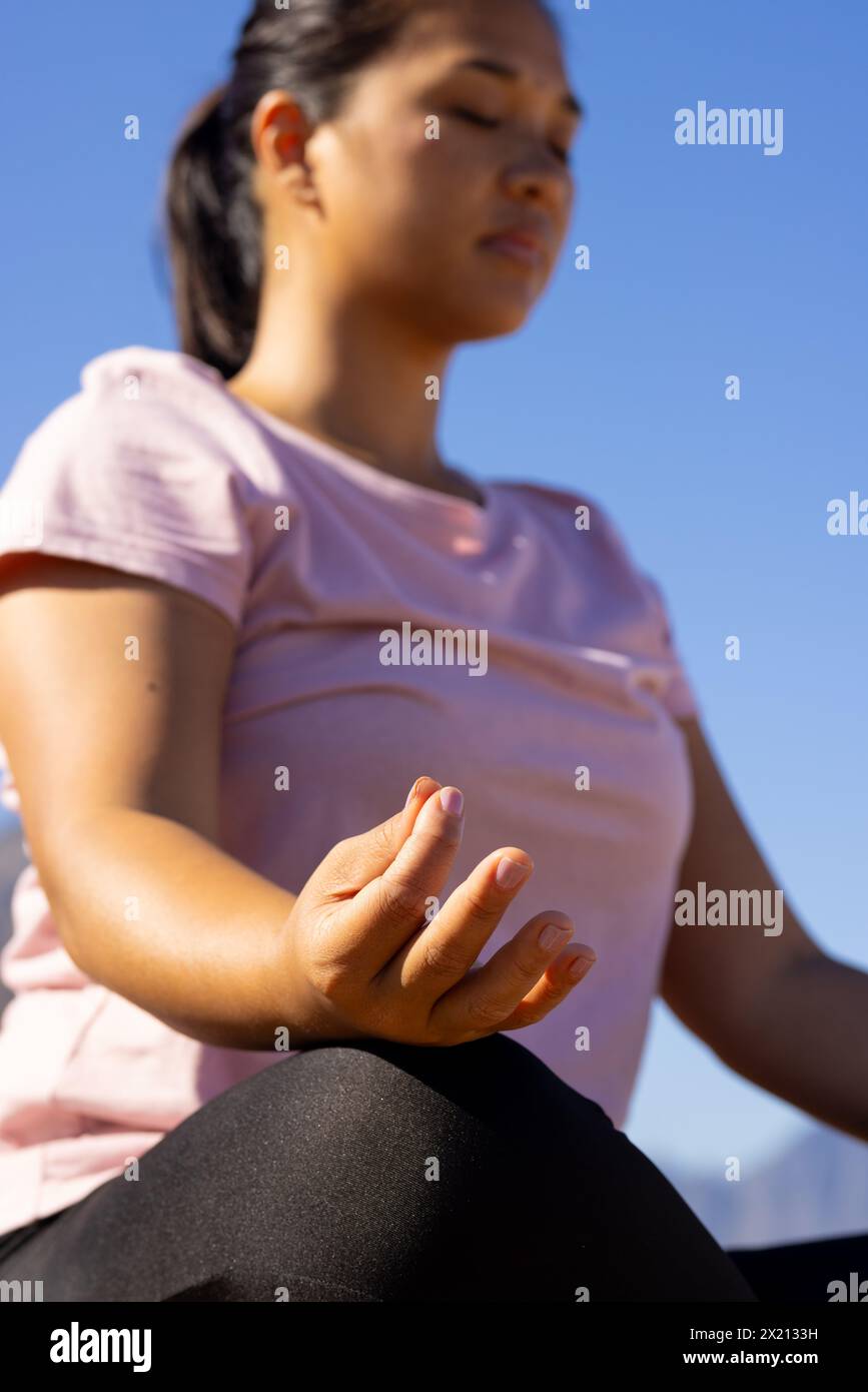 Eine birassische Wanderin, die draußen meditiert und sich auf ihre Hand konzentriert Stockfoto