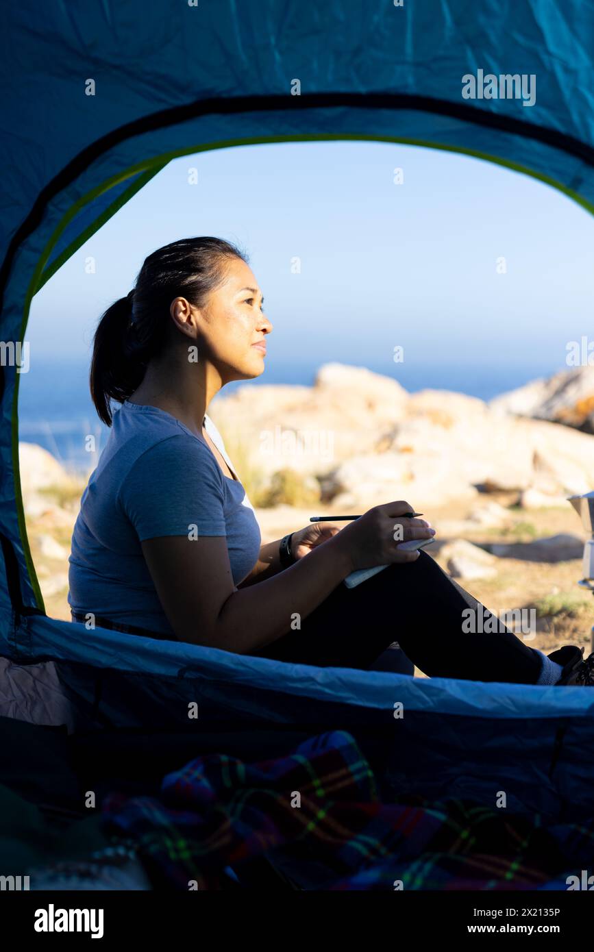 Birassische Wanderer, die im Zelt sitzt und nach draußen blickt Stockfoto