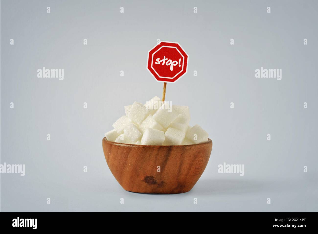 Weiße Zuckerwürfel in Holzschüssel mit Stoppschild - kein Zuckerdiät-Konzept Stockfoto