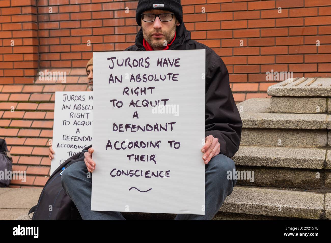 Leeds, Großbritannien. APRIL 2024. Demonstranten versammeln sich vor dem kombinierten Gericht von Leeds als Teil der Verteidigung unserer Geschworenen Proteste nachdem sie sich für ein Foto versammelt hatten, saßen die Demonstranten zu beiden Seiten des Haupteingangs des Gerichts und blockierten den Zugang nicht. Die Demonstranten hielten alle das gleiche Zeichen, dass „Geschworene ein absolutes Recht haben, einen Angeklagten nach ihrem Gewissen freizugeben“, wie bei anderen Protesten an anderen Krongerichten im ganzen Land zu sehen war. Credit Milo Chandler/Alamy Live News Stockfoto