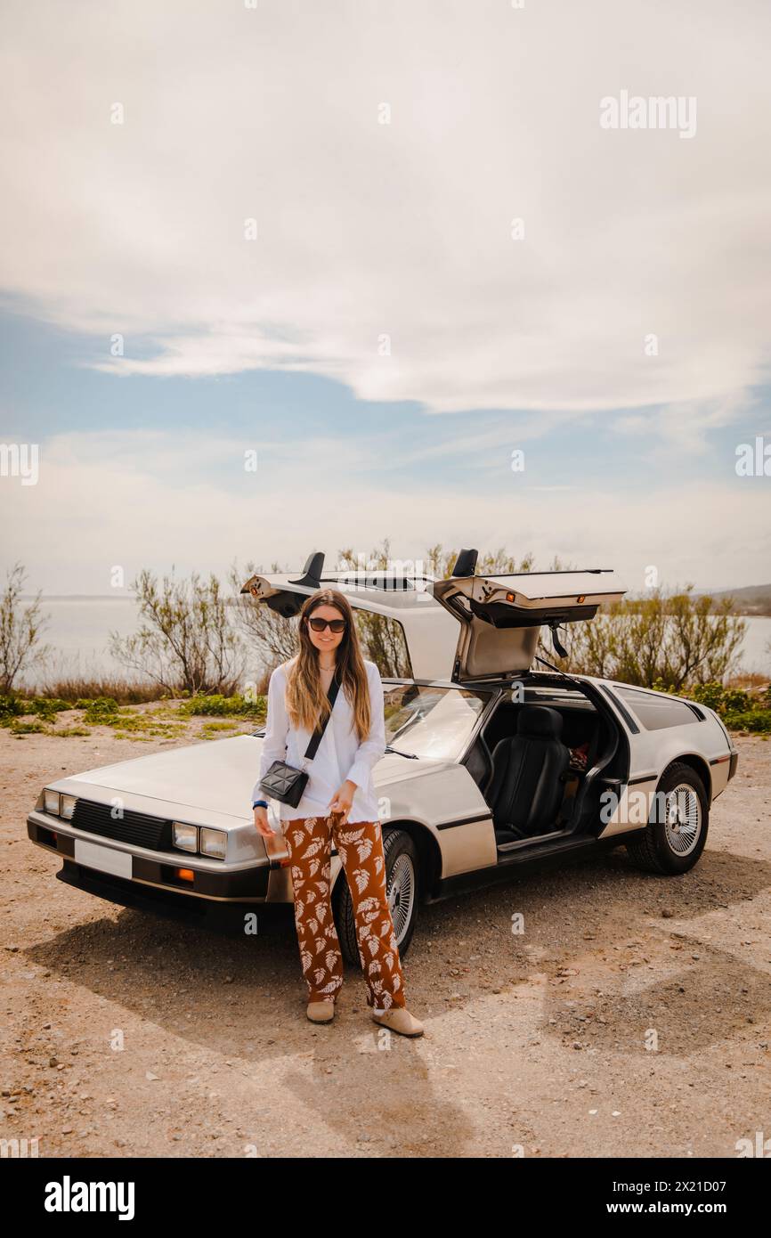 Mädchen neben dem zukünftigen Auto, das mit den Türen oben geparkt ist (DeLorean) Stockfoto