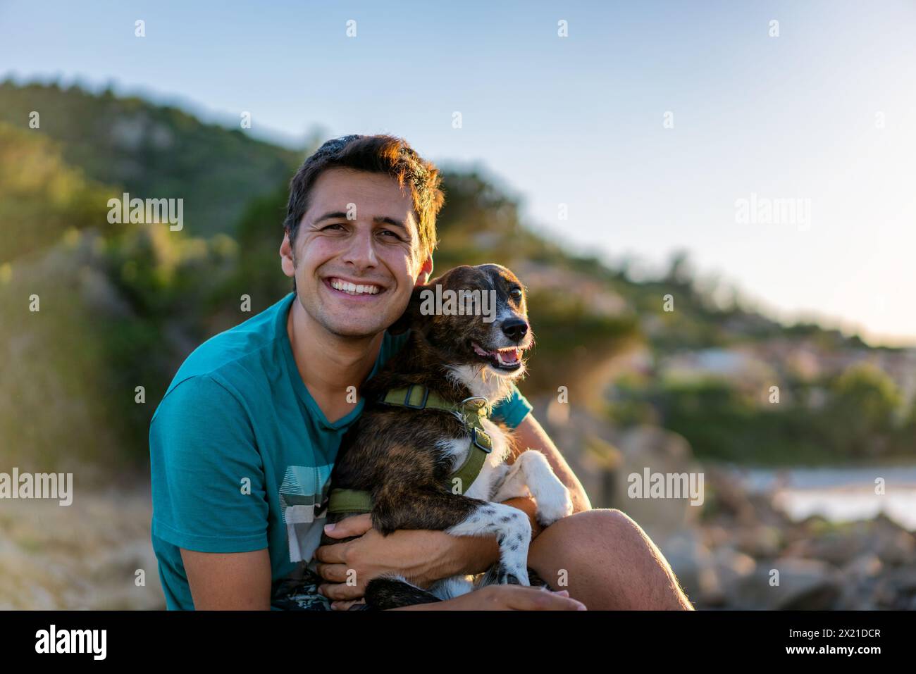 Mann und Hund lächeln in die Kamera an einer wilden Landschaft und sonnigen Tag Stockfoto