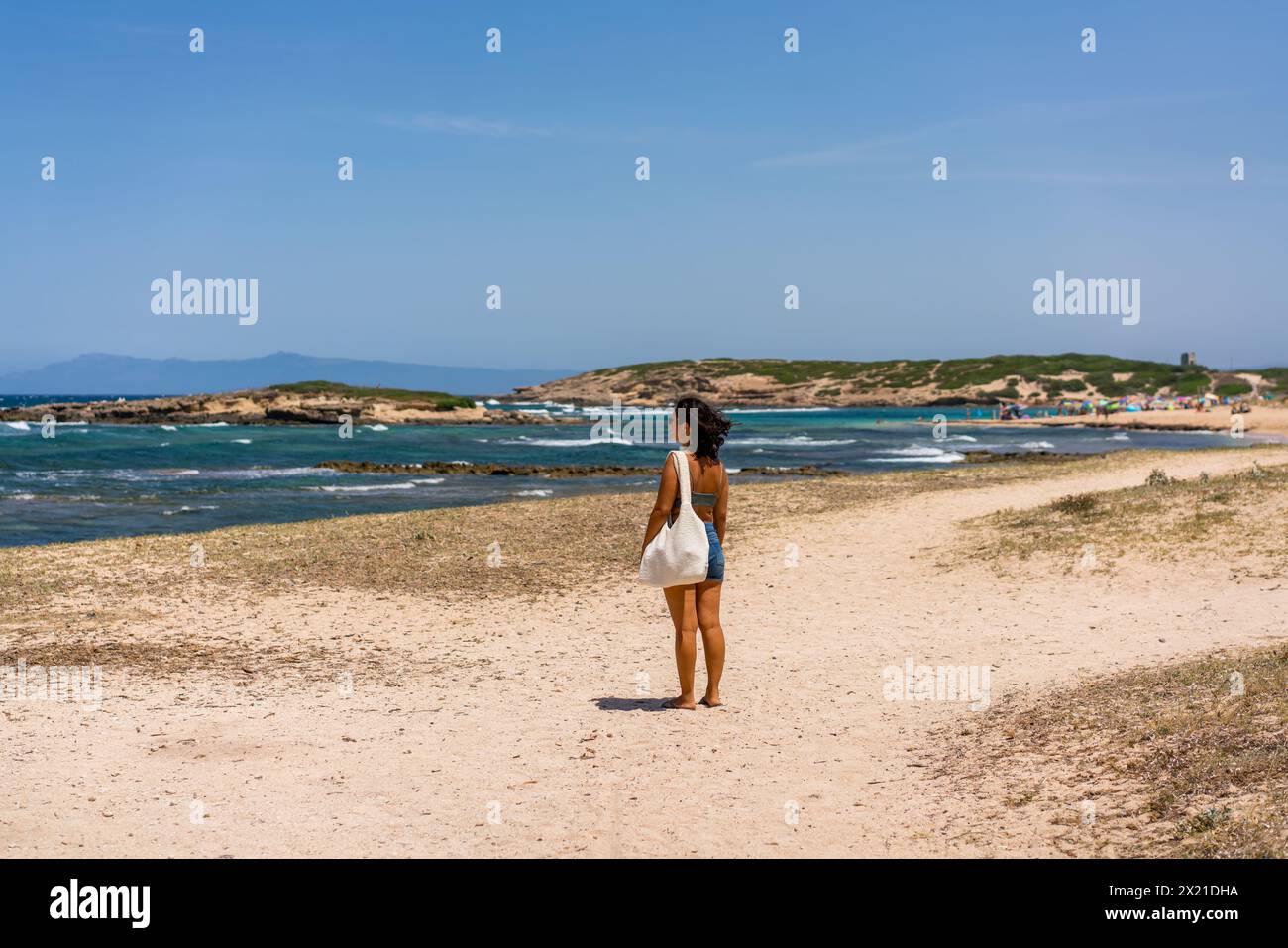 Rückansicht einer Frau mit Badeanzug an einem Strand mit türkisfarbenem Wasser Stockfoto