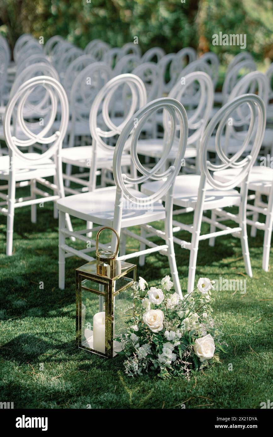 Eleganter Hochzeitsgang im Freien mit weißen Stühlen und Blumendekor Stockfoto