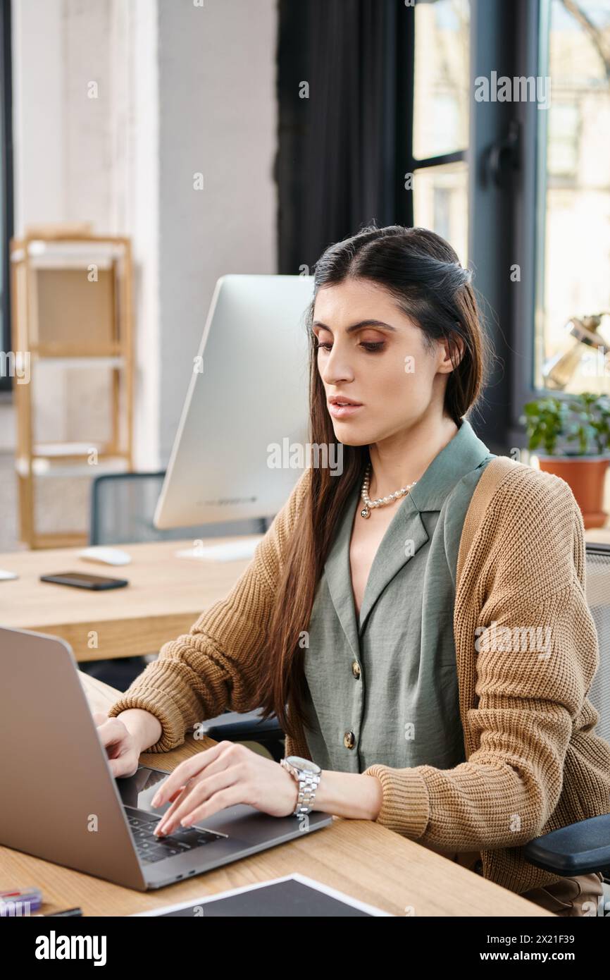 Eine Frau, die sich auf ihren Laptop konzentrierte und sich intensiv mit der Büroarbeit an einem Schreibtisch in einer Firmenumgebung beschäftigte. Stockfoto