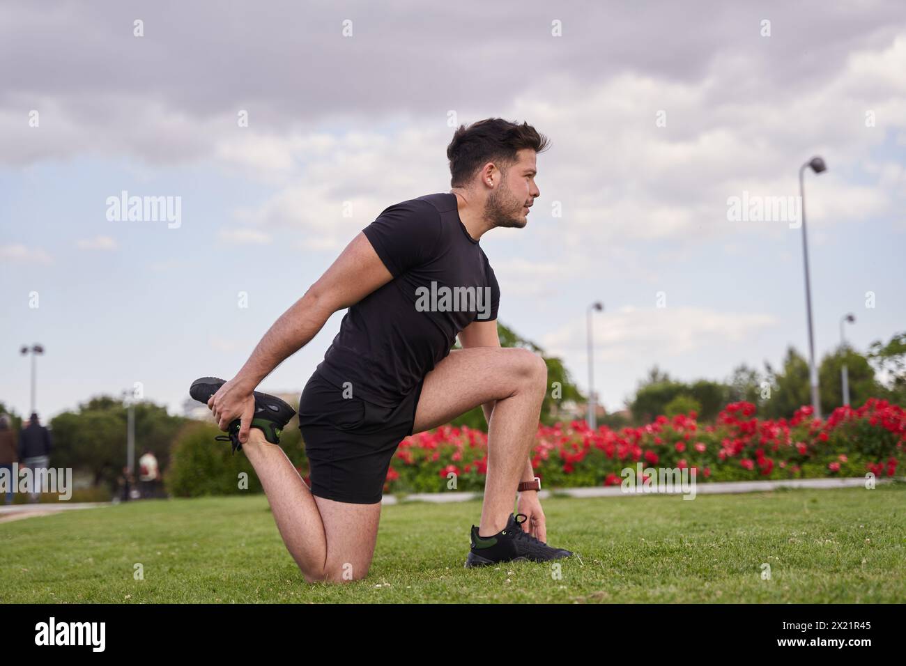 Stretching vor dem Training in einem Park im Freien. Junger latino, der sich auf das Training vorbereitet. Stockfoto