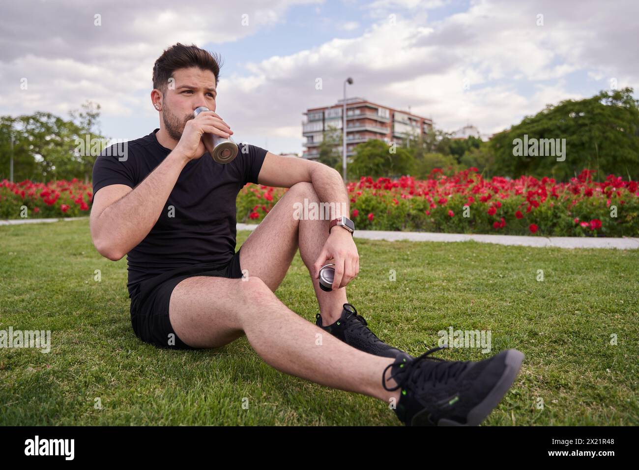 Entspannter junger Mann trinkt Wasser in einer Pause vor dem Training Stockfoto