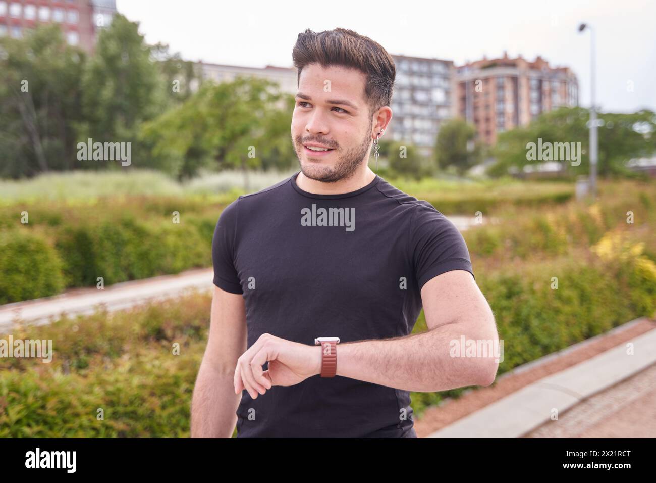 Porträt eines attraktiven jungen Latino-Athleten, der vor dem Training auf seine Uhr blickt Stockfoto