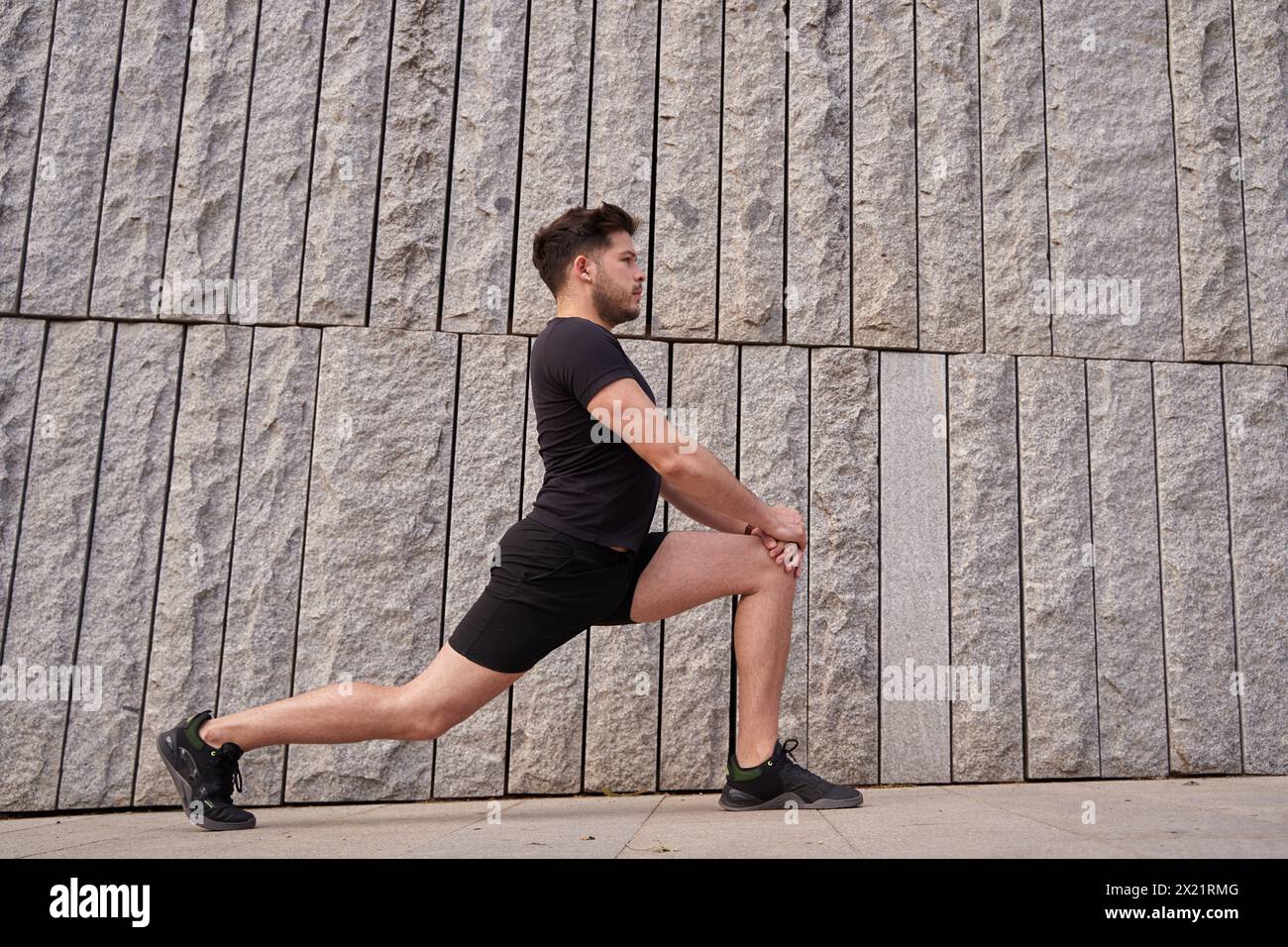 Yoga-Stretching. Mann, der sich auf einem konkreten Hintergrund ausdehnt. Stockfoto