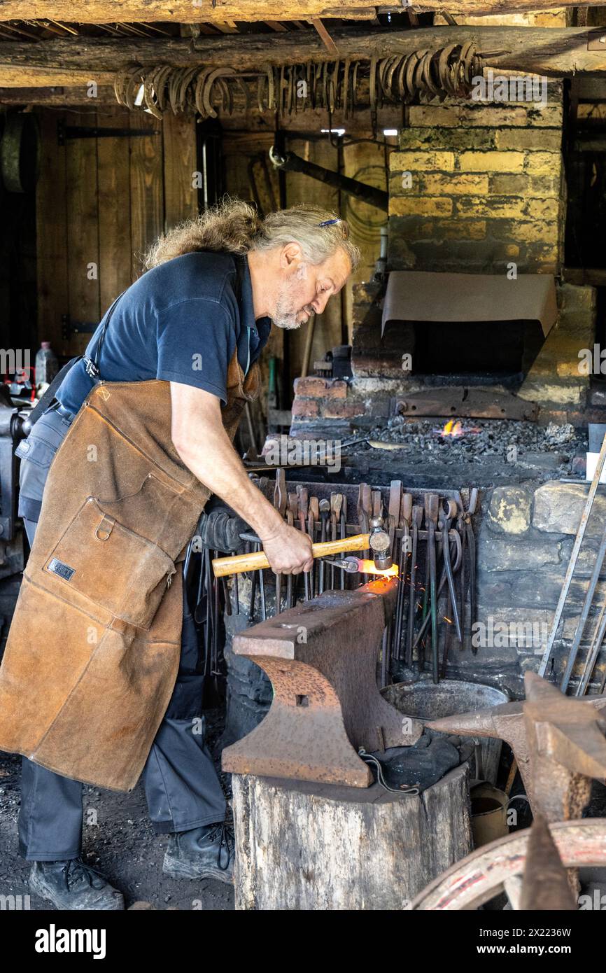 Schmied formt Metall auf einem Amboss, Weald & Downland Living Museum, West Sussex, England Stockfoto