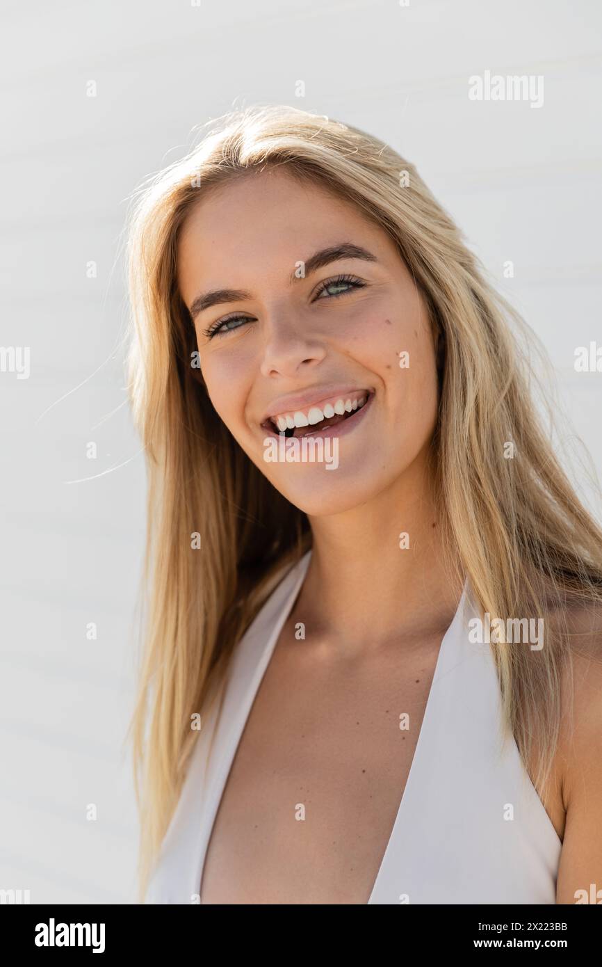 Eine junge, schöne blonde Frau in Miami Beach, die ein weißes Top trägt, lächelt warm in die Kamera. Stockfoto