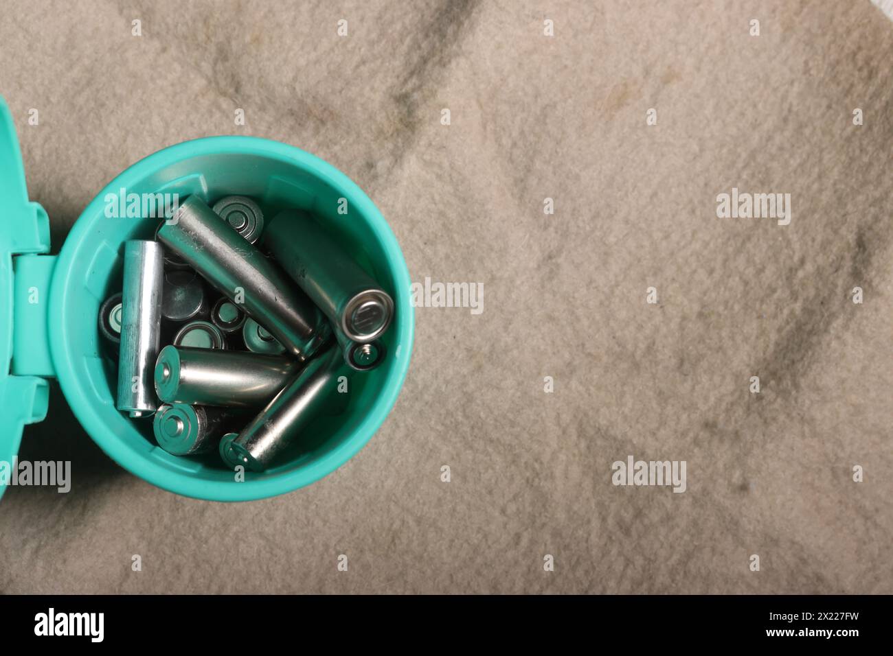 Gebrauchte Fingerbatterien in einem Miniatur-Mülleimer. Auf einem beigefarbenen schmutzigen Hintergrund. Recycling von Abfällen. Stockfoto