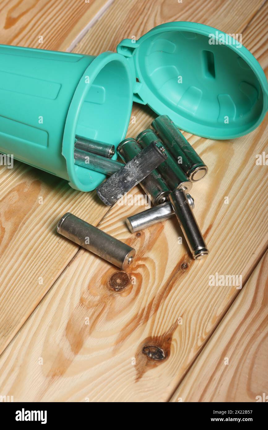 Gebrauchte Fingerbatterien in einem Miniatur-Mülleimer. Kiefernbretter. Stockfoto