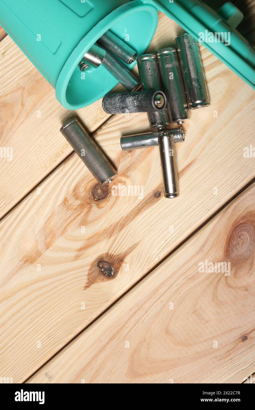 Gebrauchte Fingerbatterien in einem Miniatur-Mülleimer. Auf Pinienbrettern. Feld für Text. Stockfoto