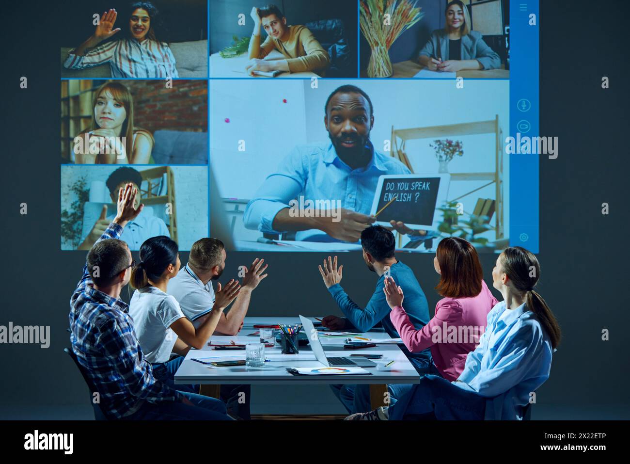 Mitarbeiter, die an einem Tisch im Sitzungssaal sitzen, nehmen an virtuellen Besprechungen Teil und haben Online-Englischunterricht für Unternehmen mit Tutor Stockfoto