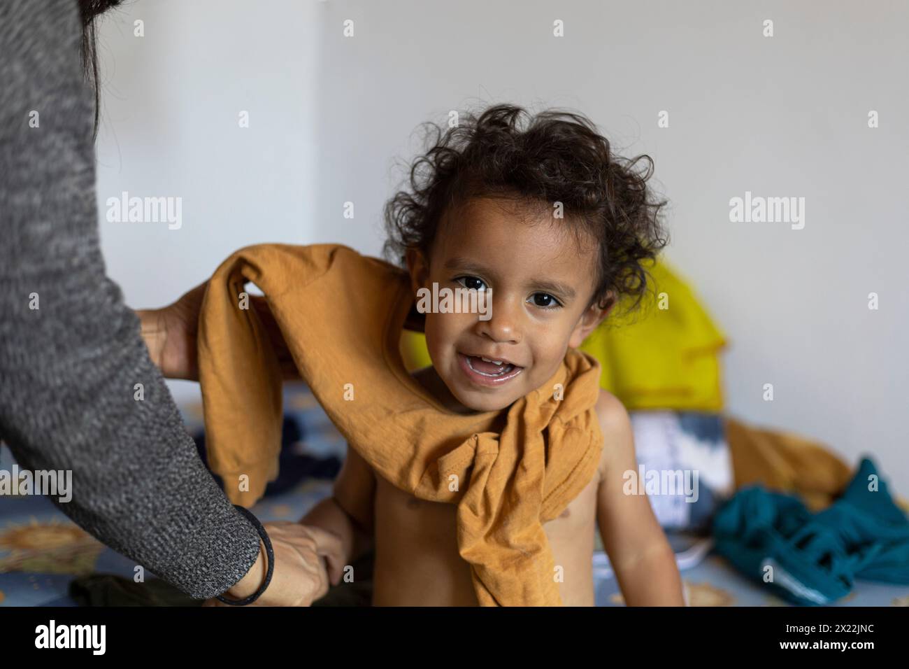 Lateinamerikanischer Junge (2) wird von seiner Mutter verändert. Konzept der Kinder- und mütterlichen Betreuung Stockfoto