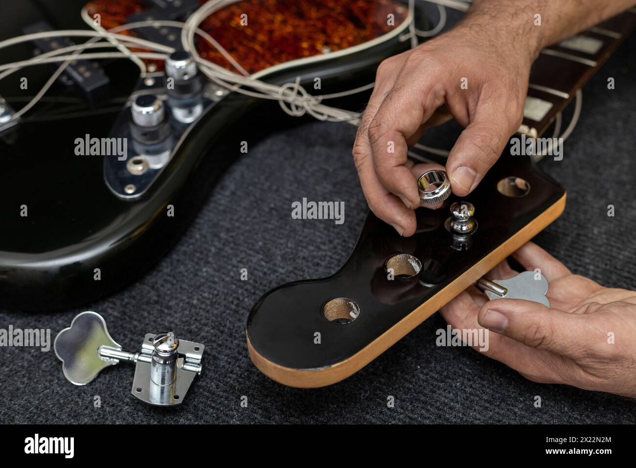 Lateinamerikanische Geigenhände, die den Stift eines E-Basses platzieren und einstellen. Nicht erkennbare Person. Konzeptreparatur, Instrument, Bass Stockfoto