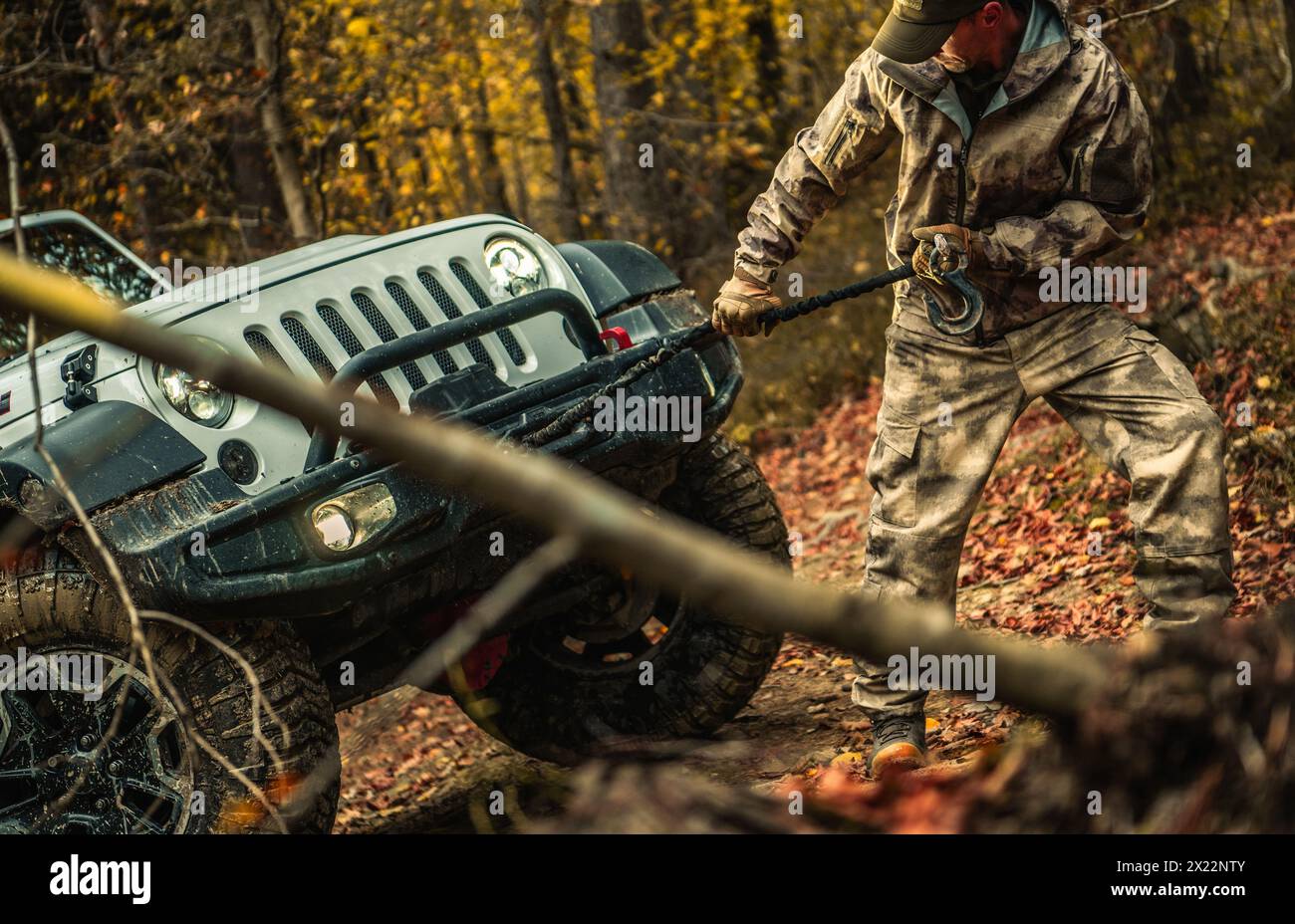 Kaukasier mit Camouflage Coat, der seinen SUV mit der Fahrzeugwinde zurückholt Stockfoto