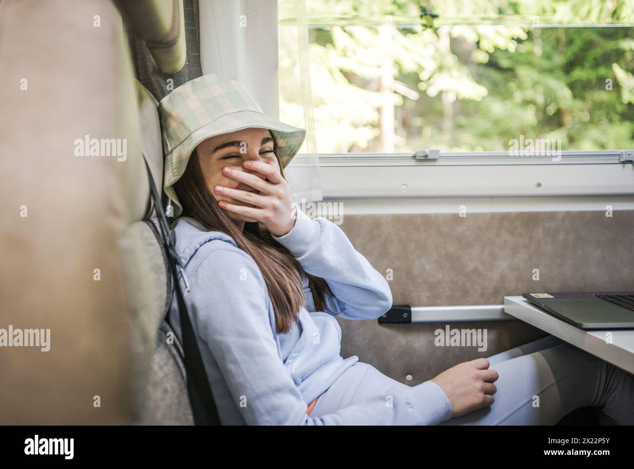 Glückliches kaukasisches Mädchen lacht, während es in einem Wohnmobil sitzt. Sommerferienthema. Stockfoto