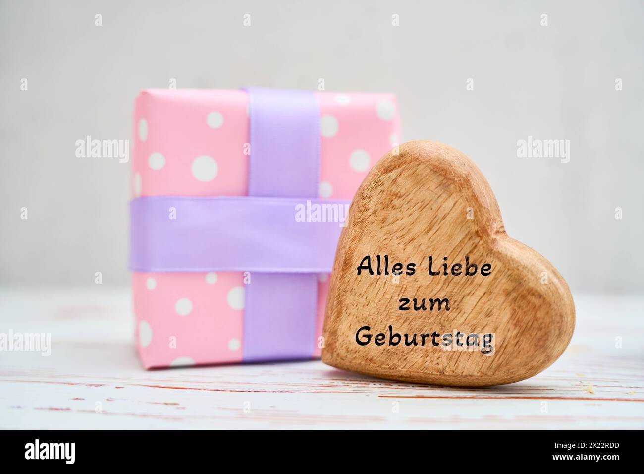 Augsburg, Bayern, Deutschland - 17. April 2024: Herzlichen Glückwunsch auf einem Herzen neben einem Geburtstagsgeschenk. FOTOMONTAGE *** alles Liebe zum Geburtstag Gruß auf einem Herz neben einem Geburtstagsgeschenk. FOTOMONTAGE Stockfoto