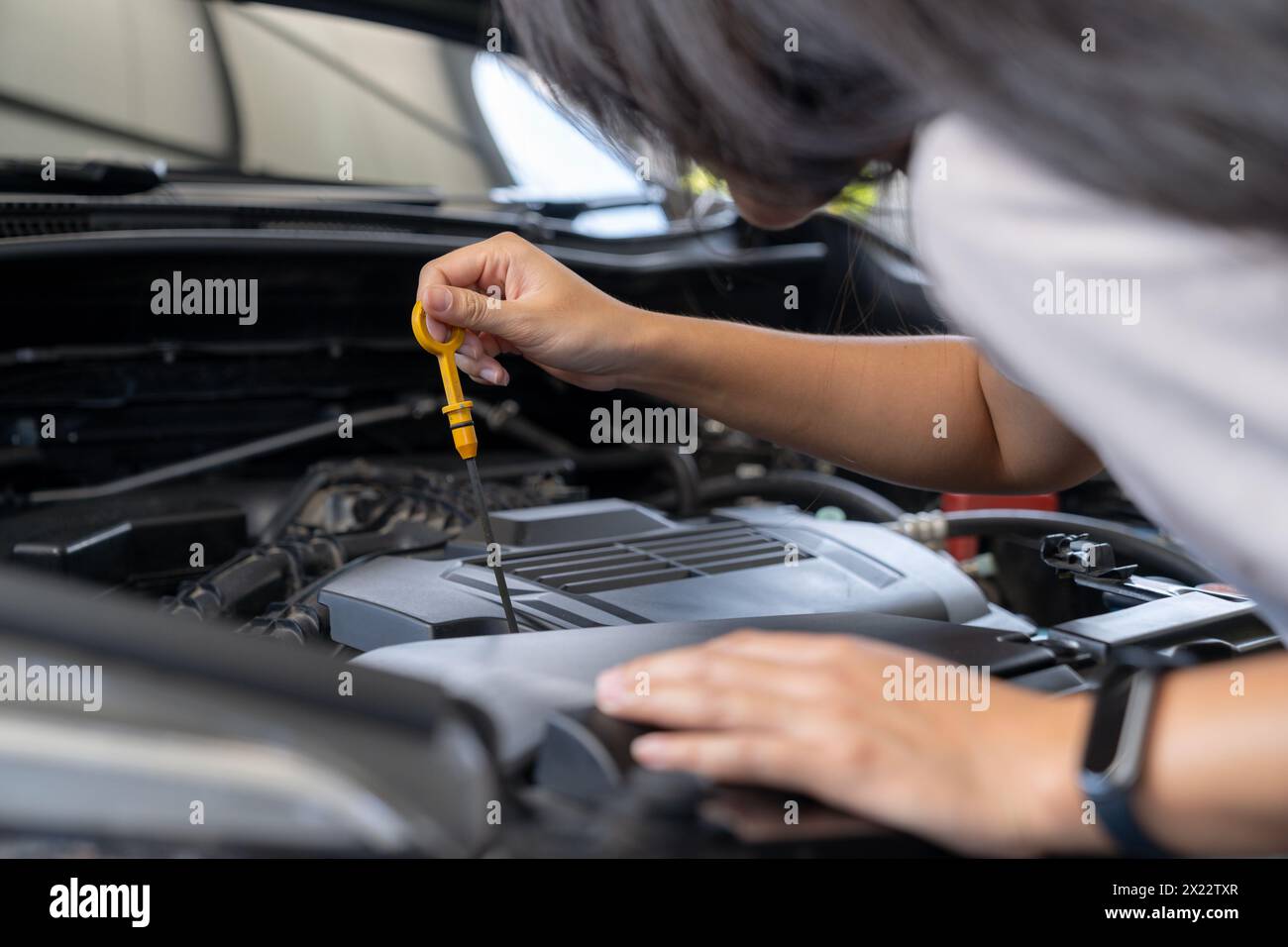 Die Frau überprüft das Motoröl des Autos Stockfoto