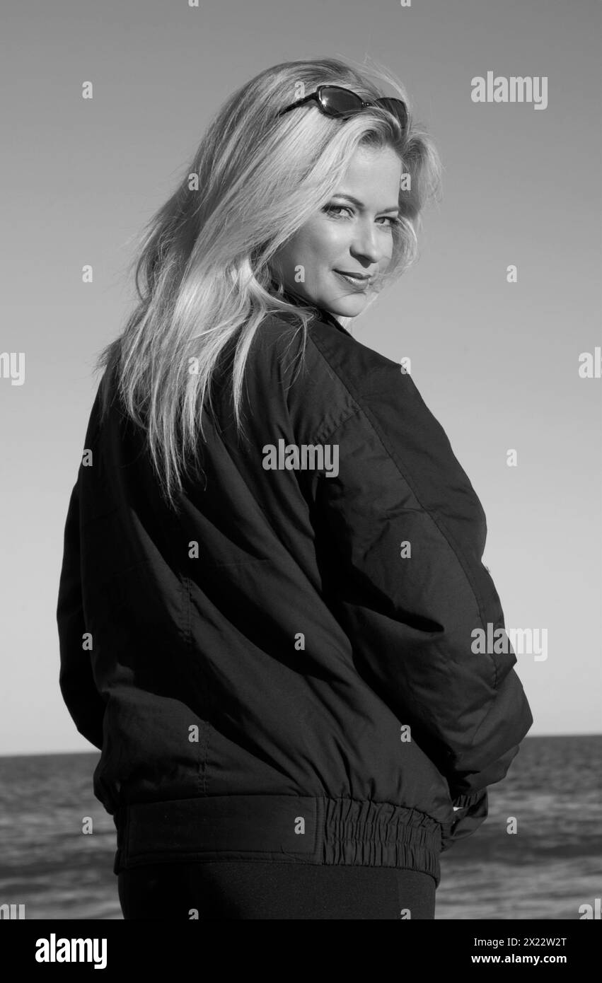 Hübsche junge blonde weiße Frau im Mantel am Hunting Island Beach in South Carolina USA Stockfoto