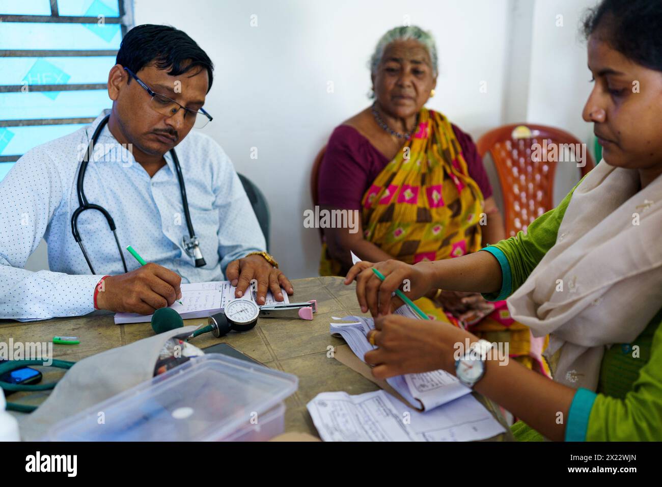 Kalkutta, Indien - 29. Oktober 2024: Ein indischer Arzt wird in einer Klinik auf dem Land gesehen, wie er eine alte Patientin berät und Medikamente verschreibt Stockfoto