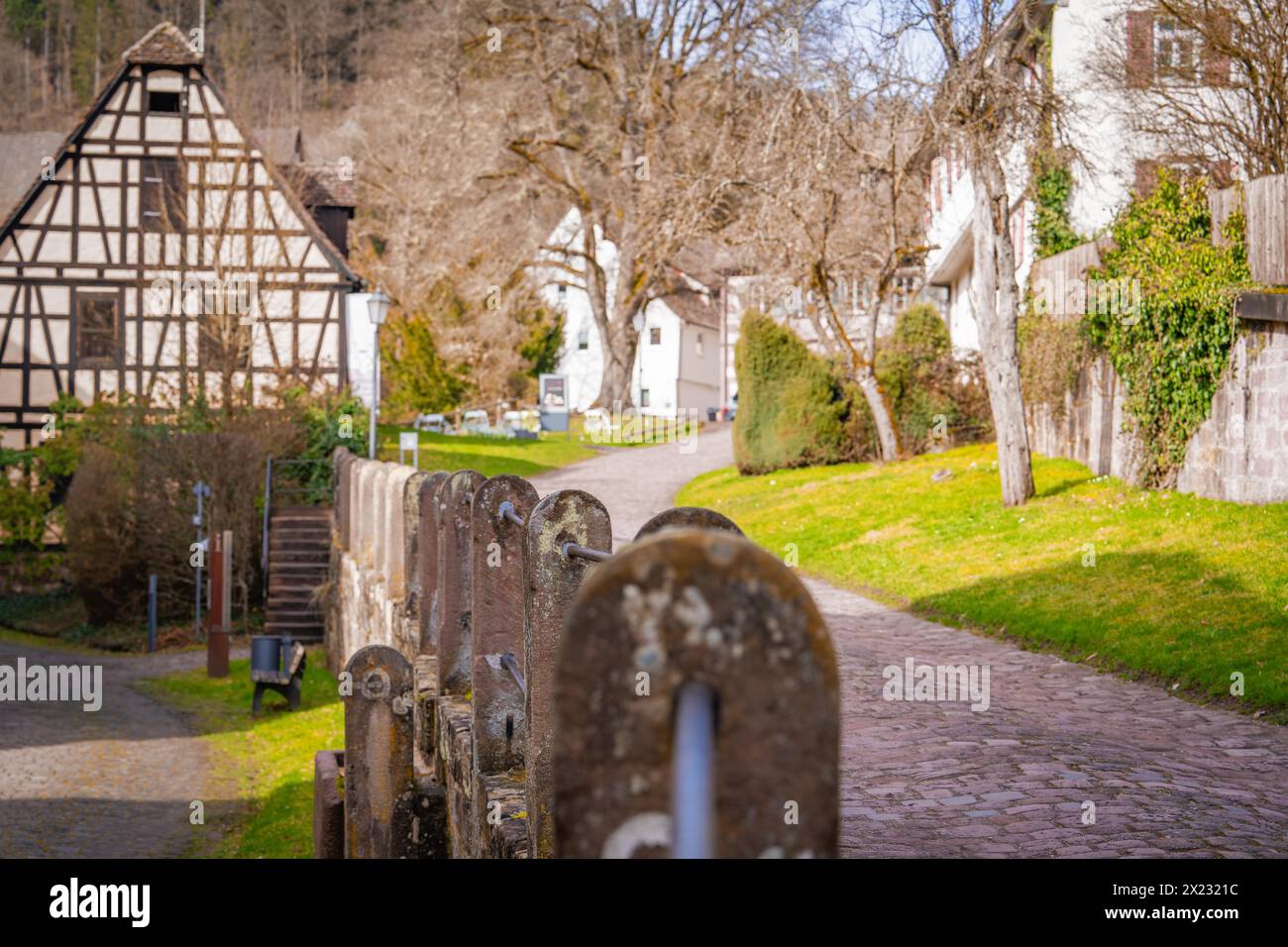 Fachwerkhaus hinter einem alten Steinzaun, das entlang einer ruhigen Dorfstraße in Calw, Schwarzwald, Deutschland führt Stockfoto