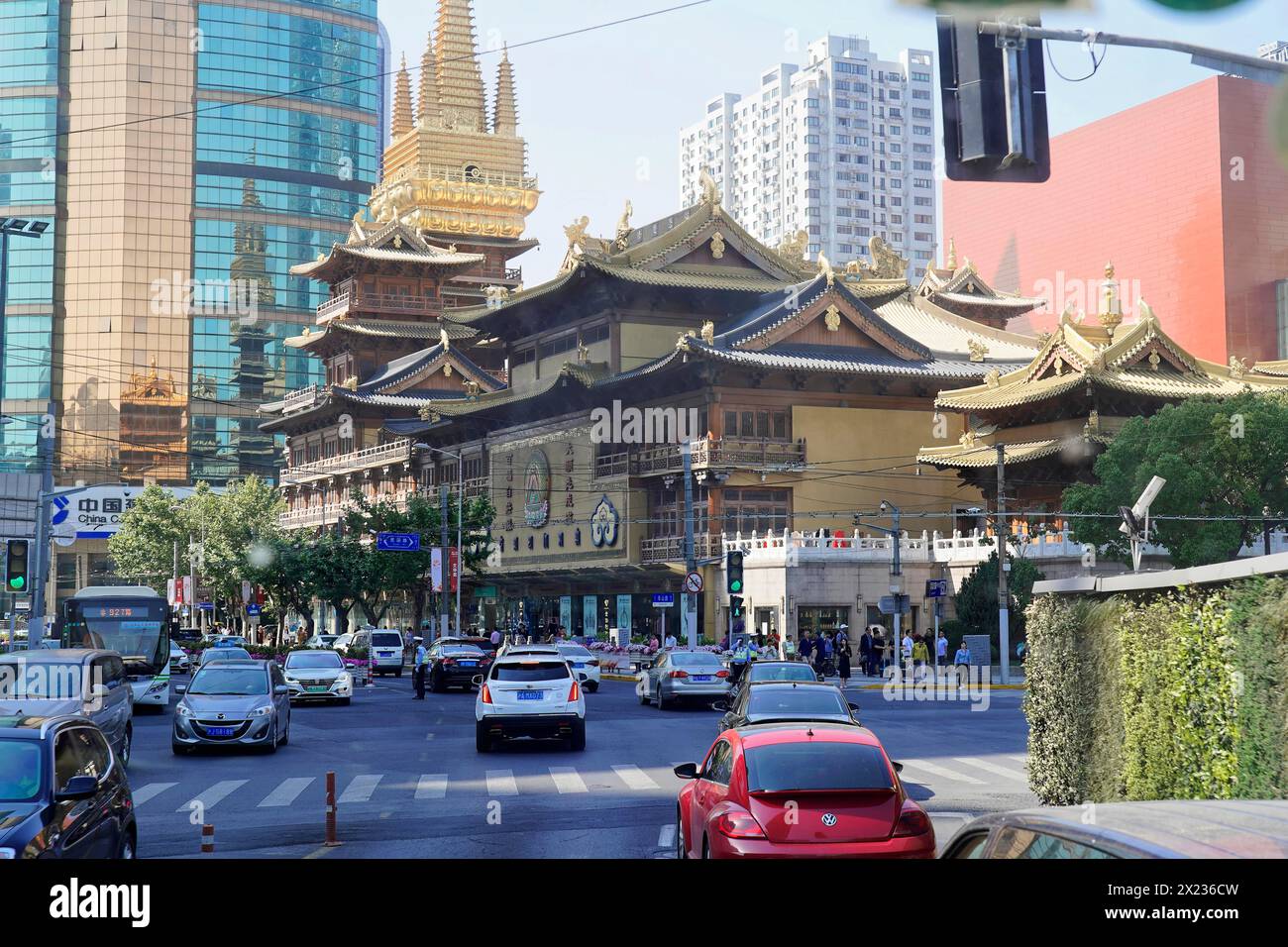 Verkehr in Shanghai, Shanghai Shi, Volksrepublik China, traditioneller Tempel vor modernen Gebäuden auf einer städtischen Straße mit Verkehr Stockfoto