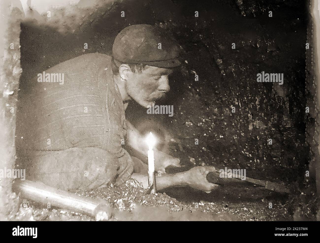 Kohlebergbau in Großbritannien. Ein altes Foto, das einen walisischen Kohlebergmann zeigt, der bei Kerzenlicht am Kohlegesicht arbeitet. Stockfoto