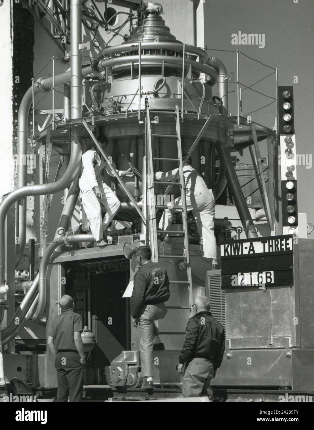 1960, Nevada - Techniker bereiten den Atomreaktor Kiwi-A3 für einen Test auf dem Wüstentestgelände von Nevada vor. Am Reaktor sind viele empfindliche Instrumente angebracht, die den Betrieb des Geräts messen, und Blinkleuchten (Bedienfeld rechts), die zur Fernüberwachung verwendet werden. Der Test dieses Kernreaktors brachte den Menschen näher an die interplanetare Raumfahrt. USIA Stockfoto