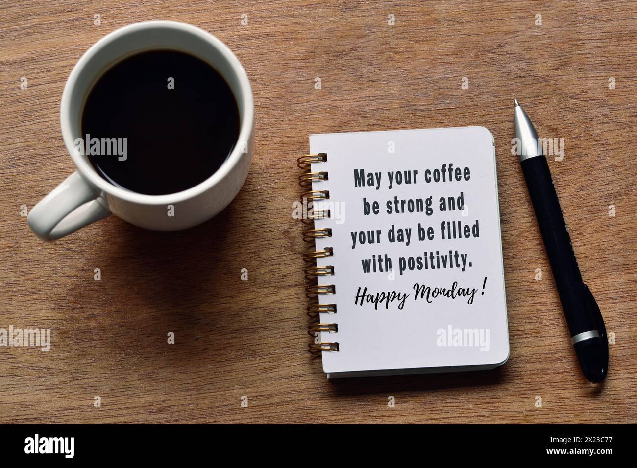 Motivierendes Zitat auf Notizblock mit Kaffeetasse und Stift auf Holztisch Mögen Sie Kaffee stark sein und Ihren Tag mit positiver Stimmung erfüllt sein, Happy monday. Stockfoto