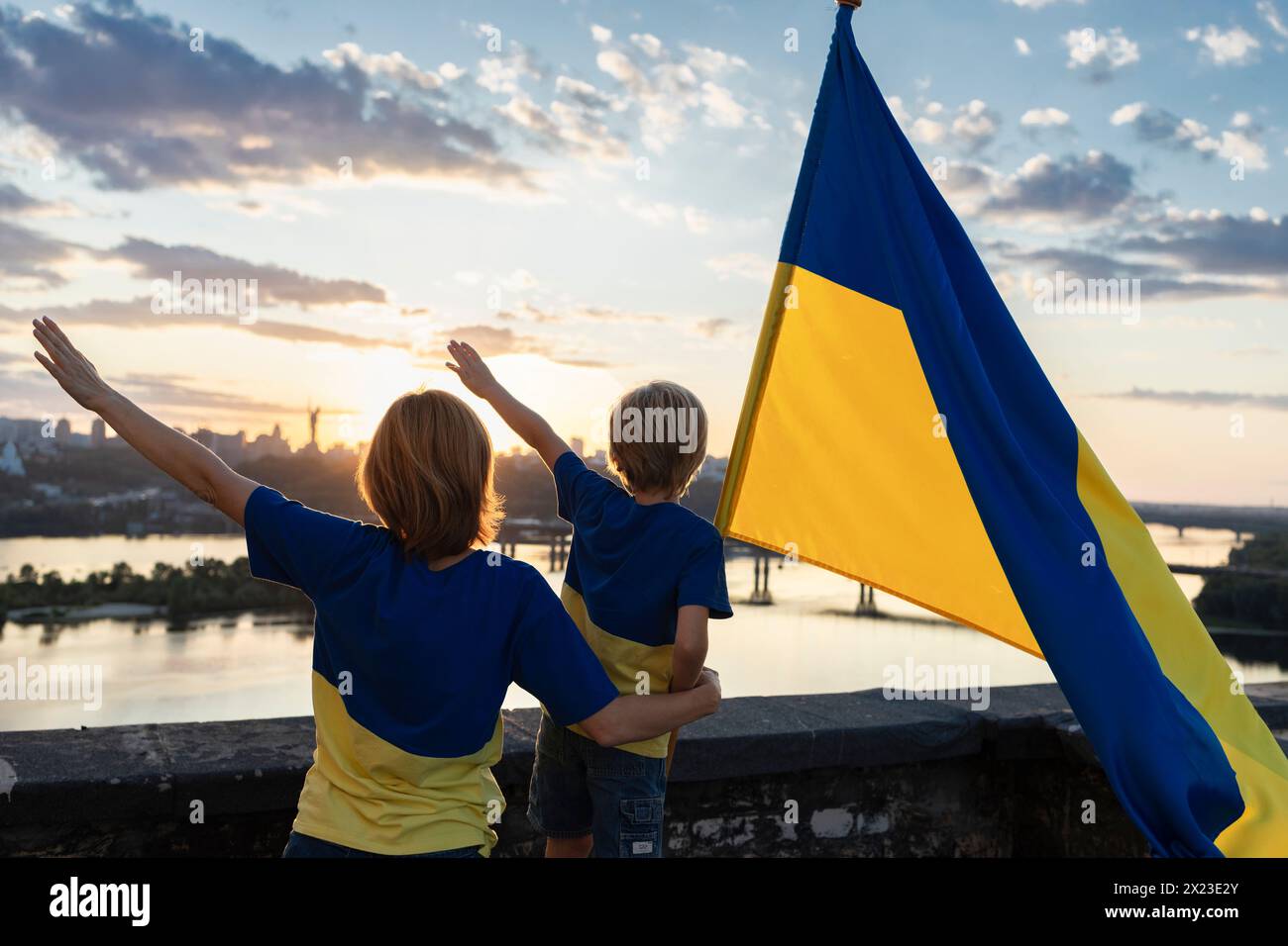 Mutter und Sohn mit der ukrainischen Flagge stehen hoch auf dem Dach vor dem Hintergrund des Himmels und des Flusses Dnieper in Kiew Stockfoto Mutter und Sohn mit der ukrainischen Flagge stehen hoch auf dem Dach vor dem Hintergrund des Himmels und des Flusses Dnieper in Kiew Stockfoto