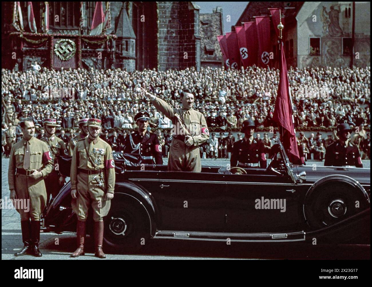 1930er Jahre Adolf Hitler in Sturmbleitungs-Uniform auf dem Rücksitz seines offenen Mercedes-Wagens, ein seltenes Farbbild von Hitler, das der vorbeiziehenden paramilitärischen Armee der Sturmbleitung einen Heil-Hitler-Gruß gibt. Rudolf Hess steht auf der linken Seite des Mercedes-Autos. Nürnberg Nürnberg Rallye Nazi Gemany 1930er Jahre Leibstandarte SS Adolf Hitler („Life Guards SS Adolf Hitler“; LSSAH) eine Elite-SS-Schutzeinheit dahinter Stockfoto