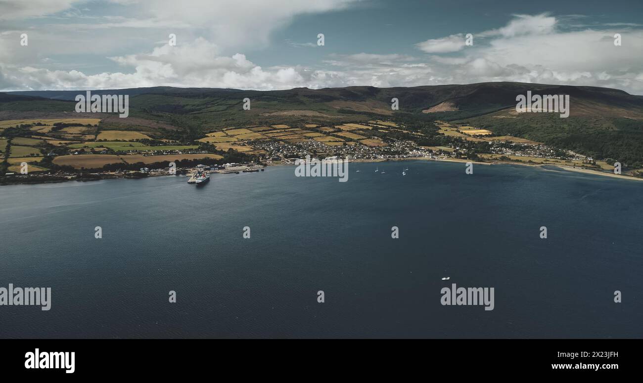 Brodick Ocean Ferry Terminal aus der Vogelperspektive: Schiffe, Boote und Segelboote auf der Meeresoberfläche im Hafen. Wundervolle schottische Naturlandschaft mit Wäldern und Tälern im Sommer Stockfoto