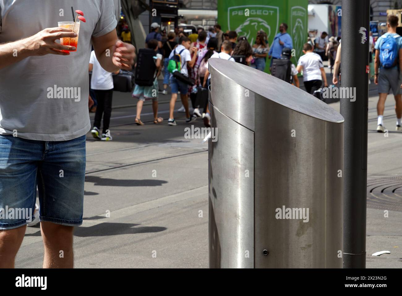 Ein Mann warf etwas in einen Street Metal Mülleimer. Seine Hand ist unfokussiert, weil sie sich noch in Bewegung befindet. Stockfoto